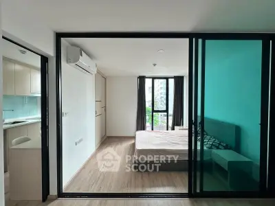 Modern apartment with sliding glass doors separating bedroom and kitchen, featuring sleek design and natural light.
