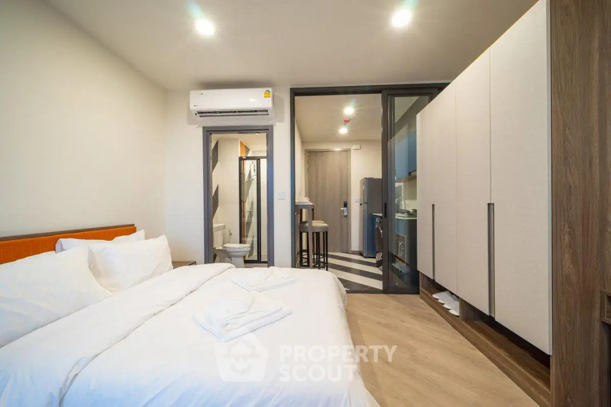Modern bedroom with ensuite bathroom and compact kitchen in a stylish apartment.