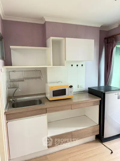 Modern compact kitchen with microwave and fridge in stylish apartment
