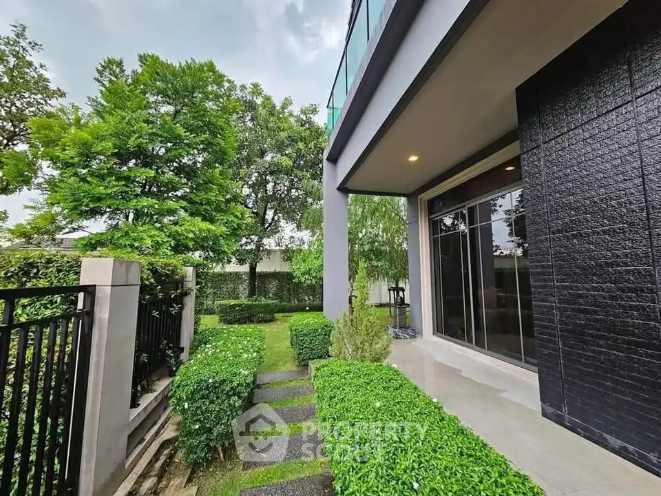 Modern home exterior with lush garden and sleek black facade, perfect for contemporary living.
