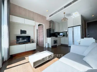 Modern living room with open kitchen, sleek furniture, and abundant natural light in a stylish apartment.