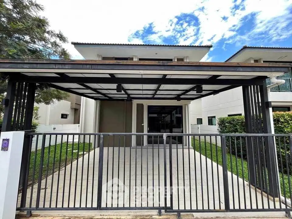 Modern house exterior with gated driveway and lush greenery