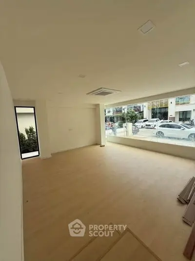 Spacious unfurnished room with large window offering street view, ideal for versatile use.