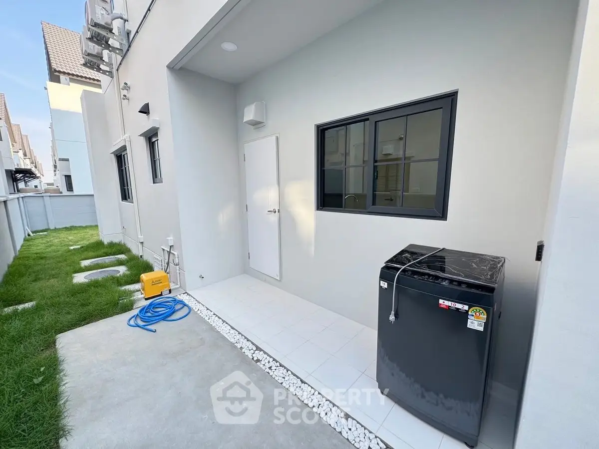 Modern exterior with washing machine and green lawn in a residential area.