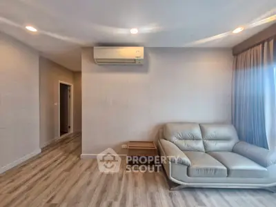 Modern living room with sleek sofa and air conditioning, featuring elegant wood flooring.