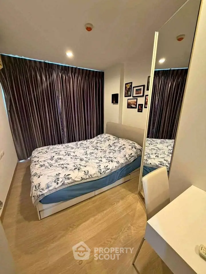 Cozy bedroom with modern decor and large mirror reflecting natural light.