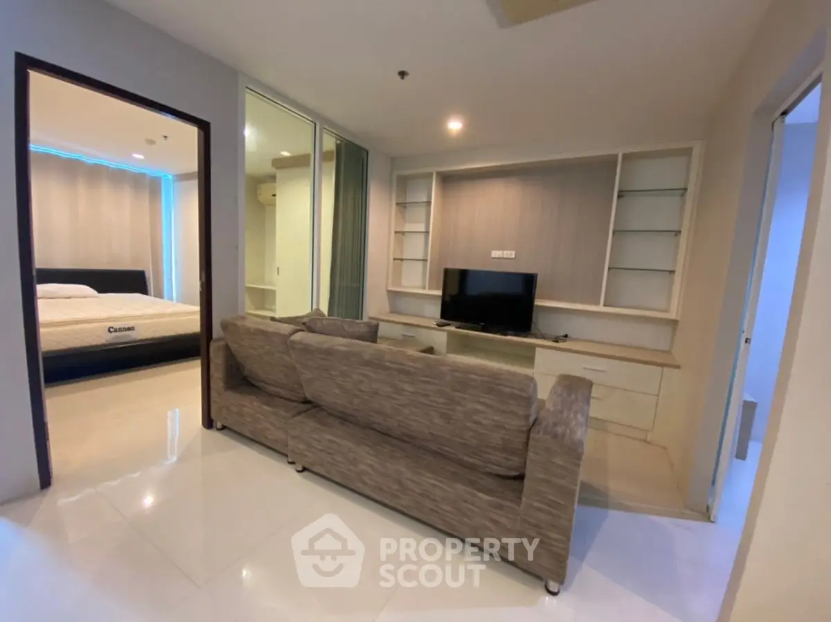 Modern living room with cozy sofa and TV, adjacent to a stylish bedroom in a contemporary apartment.