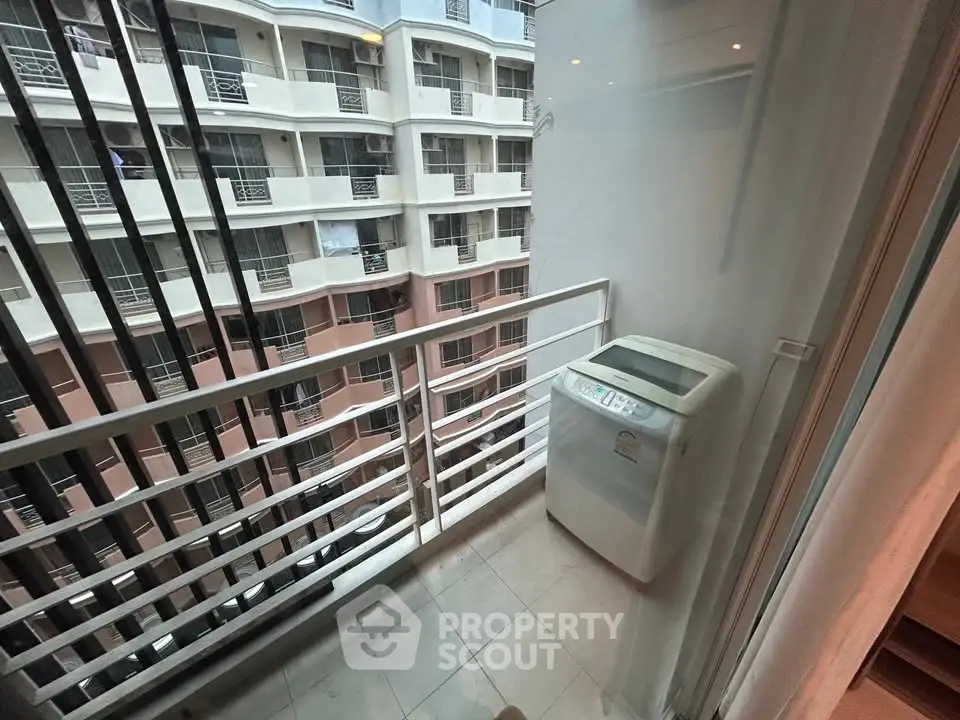 Compact balcony with washing machine in urban apartment setting.