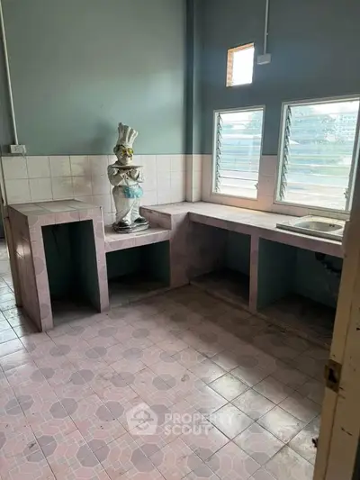 Spacious kitchen with unique tiled countertops and large windows for natural light.