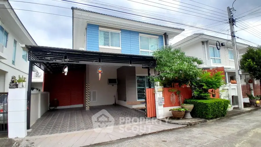 Charming two-story house with carport and lush greenery in a serene neighborhood.