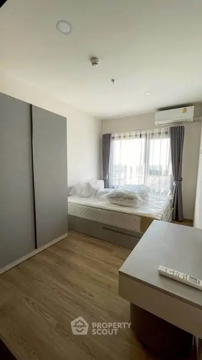 Modern bedroom with large window and minimalist design in a bright apartment.