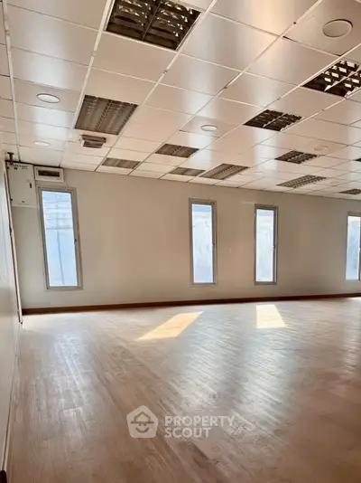 Spacious empty room with natural light and modern ceiling design, ideal for office or studio space.