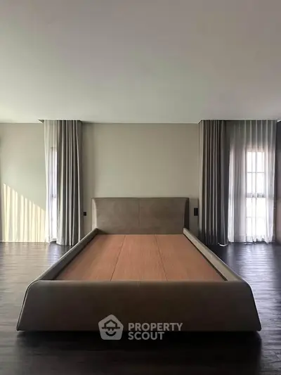 Spacious bedroom with modern bed frame and elegant floor-to-ceiling curtains
