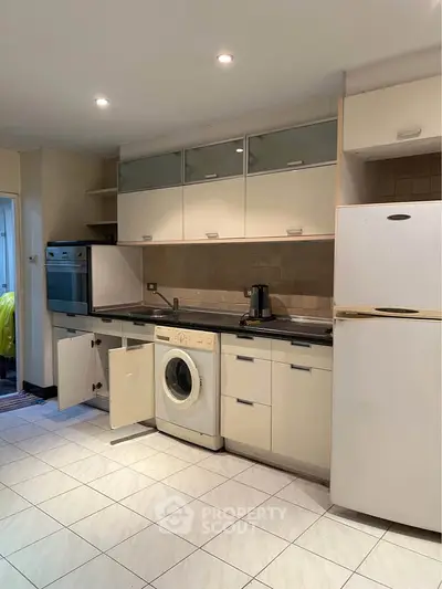 Modern kitchen with white cabinets, built-in oven, and washing machine for convenient living.