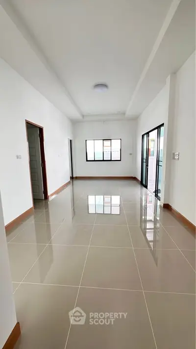 Spacious modern living room with glossy tiled floors and large windows for natural light.