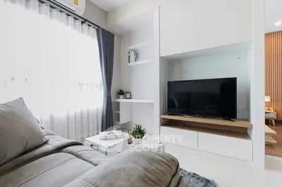 Modern living room with sleek furniture and large TV, perfect for relaxation and entertainment.