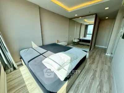 Modern bedroom with large mirror and natural light in stylish apartment.