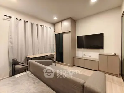 Modern living room with sleek furniture and wall-mounted TV in a cozy apartment setting.