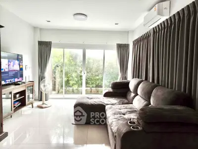 Spacious living room with plush sofa and large windows overlooking greenery, perfect for relaxation.