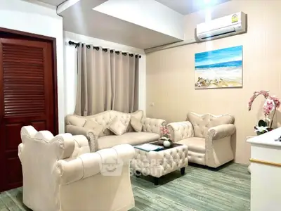 Luxurious living room with elegant beige furniture and beach-themed artwork, perfect for relaxation.