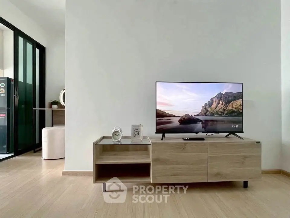 Modern living room with sleek TV stand and scenic view on screen, showcasing minimalist decor and wooden flooring.