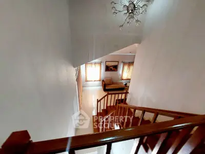 Spacious living area with elegant staircase and modern chandelier, perfect for stylish living.