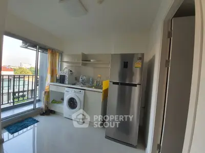 Modern kitchen with stainless steel fridge and washing machine, open layout with balcony view.