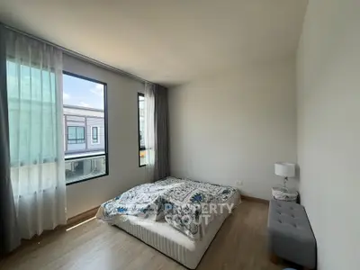 Spacious bedroom with large windows and modern decor in a contemporary home.