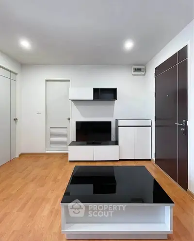 Modern minimalist living room with sleek black and white furniture and wooden flooring.