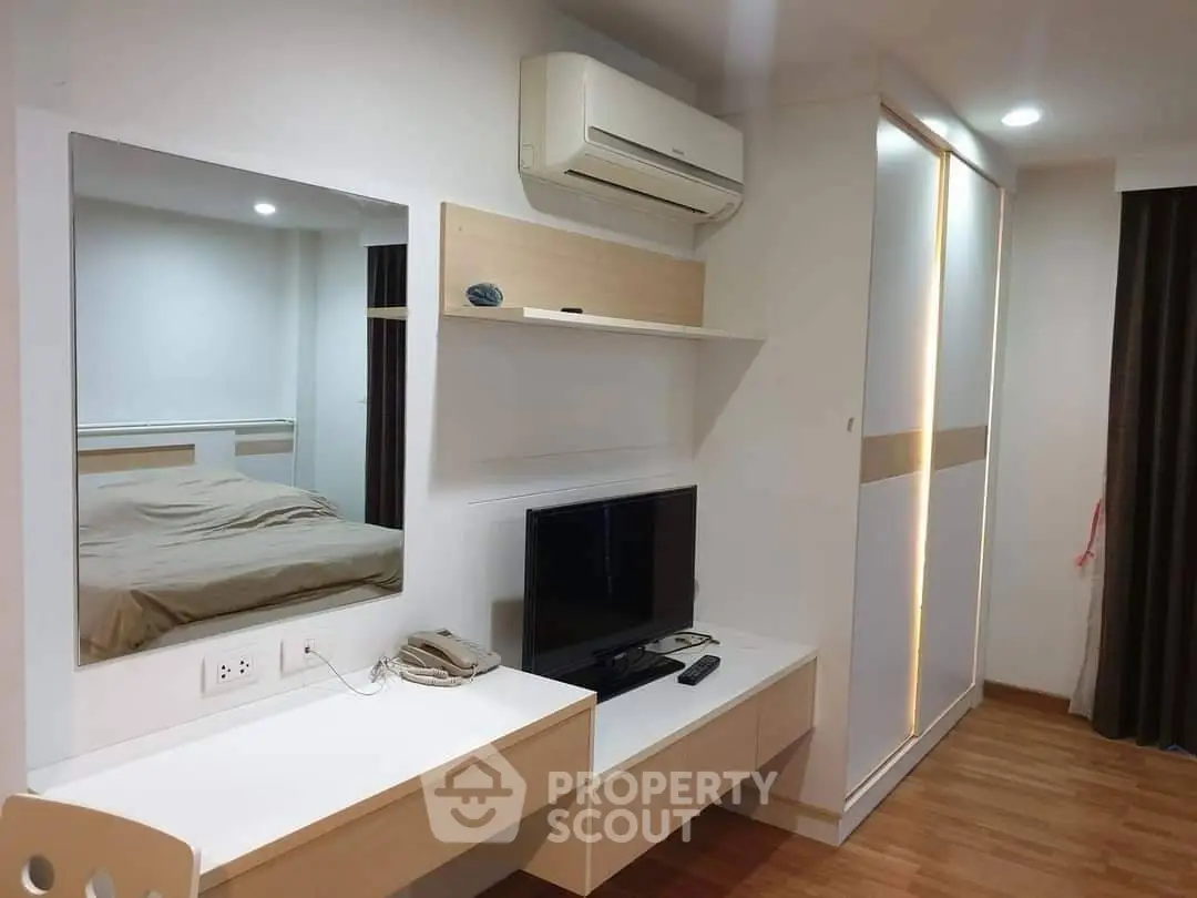 Modern bedroom with sleek design, featuring built-in wardrobe, wall-mounted TV, and air conditioning.