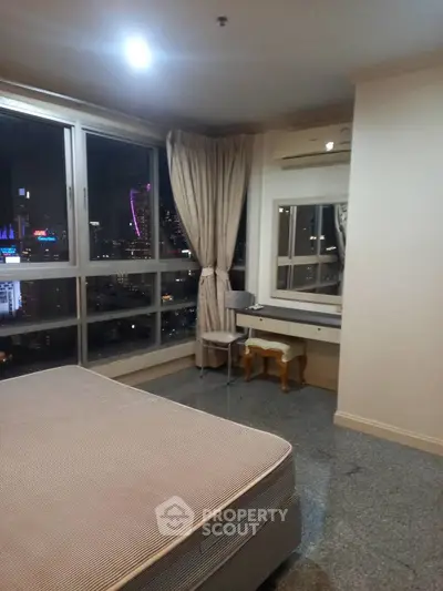 Spacious bedroom with city skyline view and elegant furnishings.