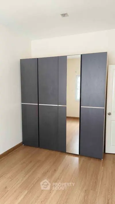 Spacious bedroom with sleek modern wardrobe and wooden flooring