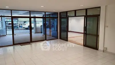 Spacious open-plan living area with large windows and tiled flooring