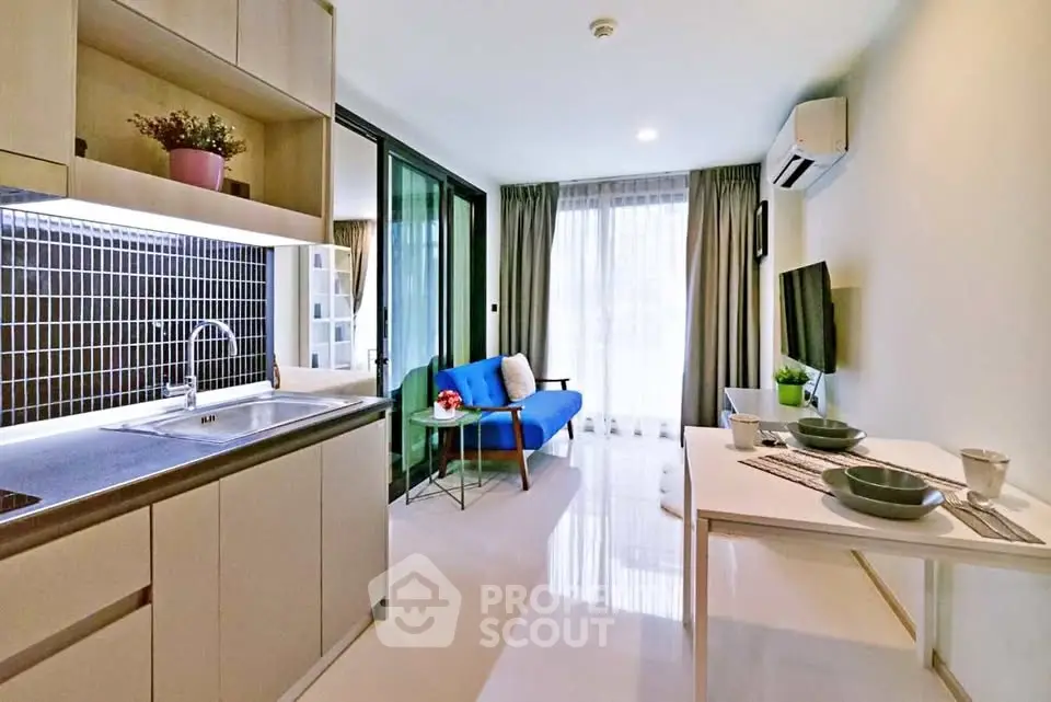 Modern open-layout living room with kitchen, featuring sleek design and natural light.