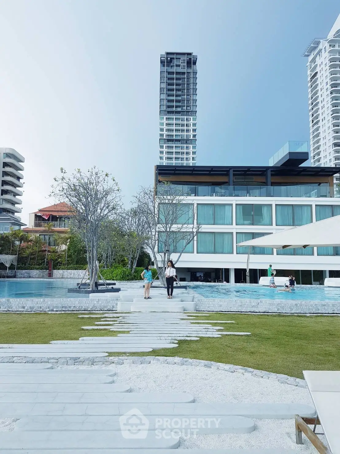 Luxurious modern building with pool and lush greenery, perfect for upscale living.