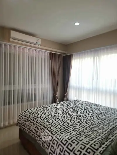 Cozy bedroom with large windows and elegant curtains, featuring a comfortable bed and air conditioning for ultimate comfort.