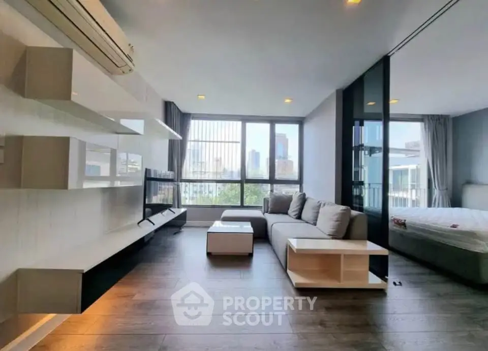 Modern living room with city view, featuring sleek furniture and large windows for natural light.