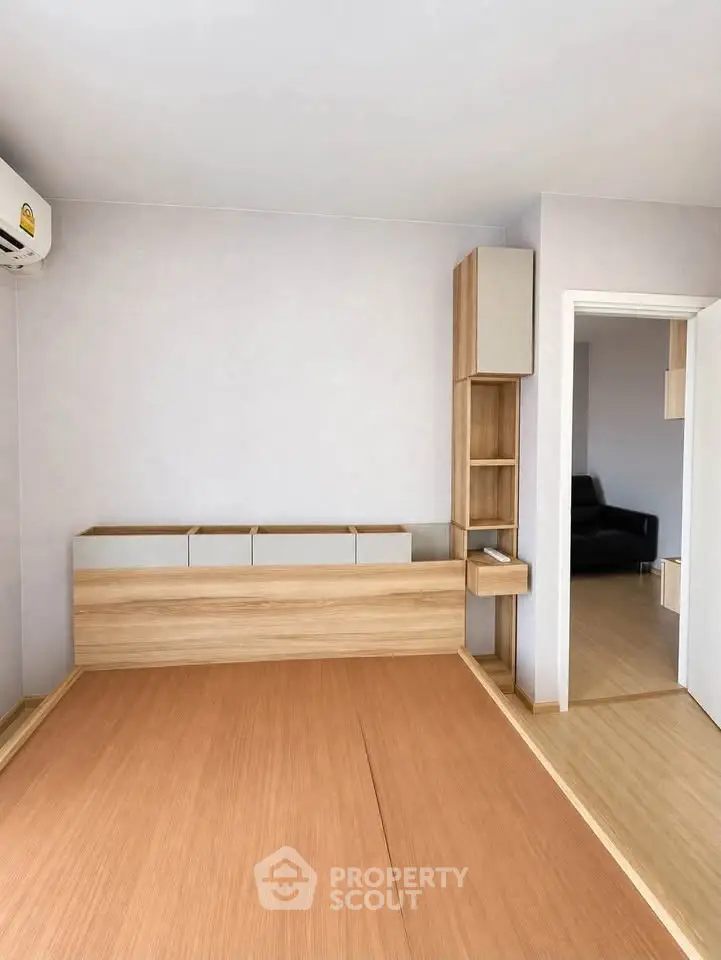 Modern minimalist bedroom with wooden flooring and built-in storage solutions.