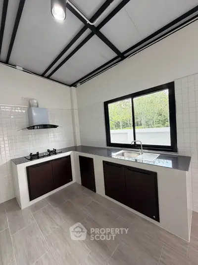 Modern kitchen with sleek design and gas stove, featuring large window for natural light.