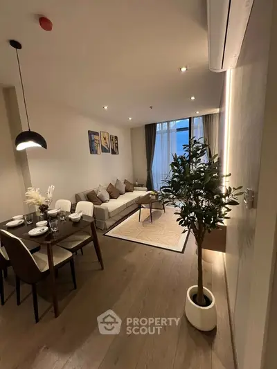 Modern living room with elegant dining area and cozy seating, featuring stylish decor and ambient lighting.