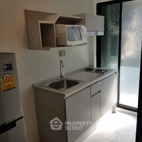 Modern compact kitchen with sleek cabinetry and stainless steel appliances in a bright apartment.
