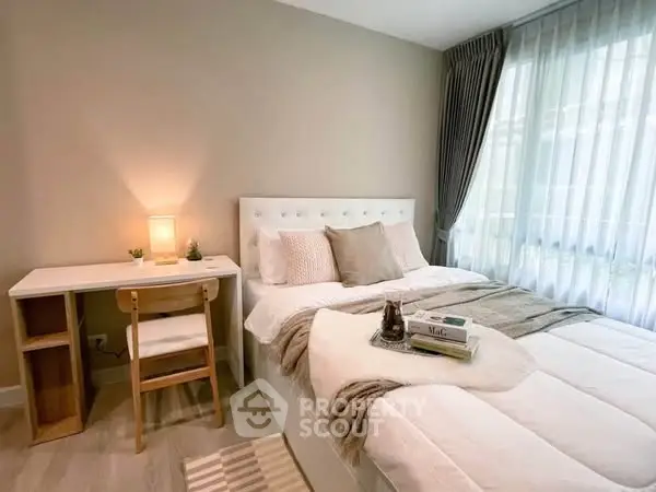 Cozy bedroom with stylish decor and natural light, featuring a comfortable bed and a small study desk.