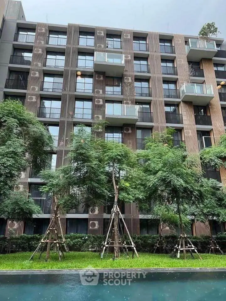 Modern apartment building with lush garden and pool view, featuring contemporary design and private balconies.