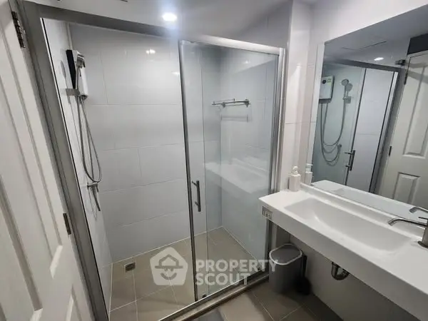 Modern bathroom with glass shower and sleek vanity in contemporary home.
