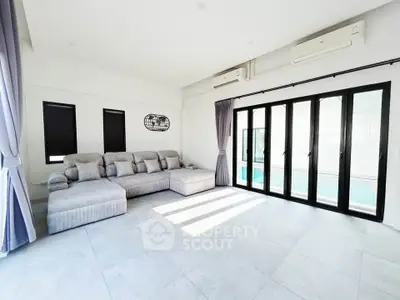 Spacious modern living room with large windows and pool view, perfect for relaxation and entertainment.