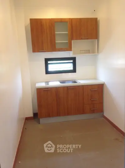 Compact kitchen with wooden cabinets and small window, ideal for cozy apartments.