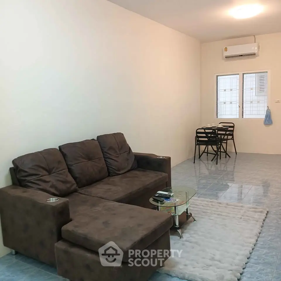 Spacious living room with cozy brown sofa and modern dining area, perfect for relaxation and entertaining.