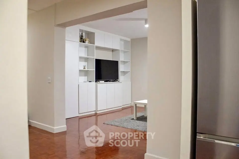 Modern living room with sleek white cabinetry and hardwood floors.