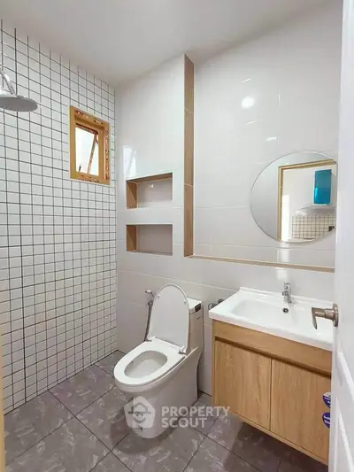 Modern bathroom with sleek design, featuring a round mirror and wooden vanity for a stylish touch.