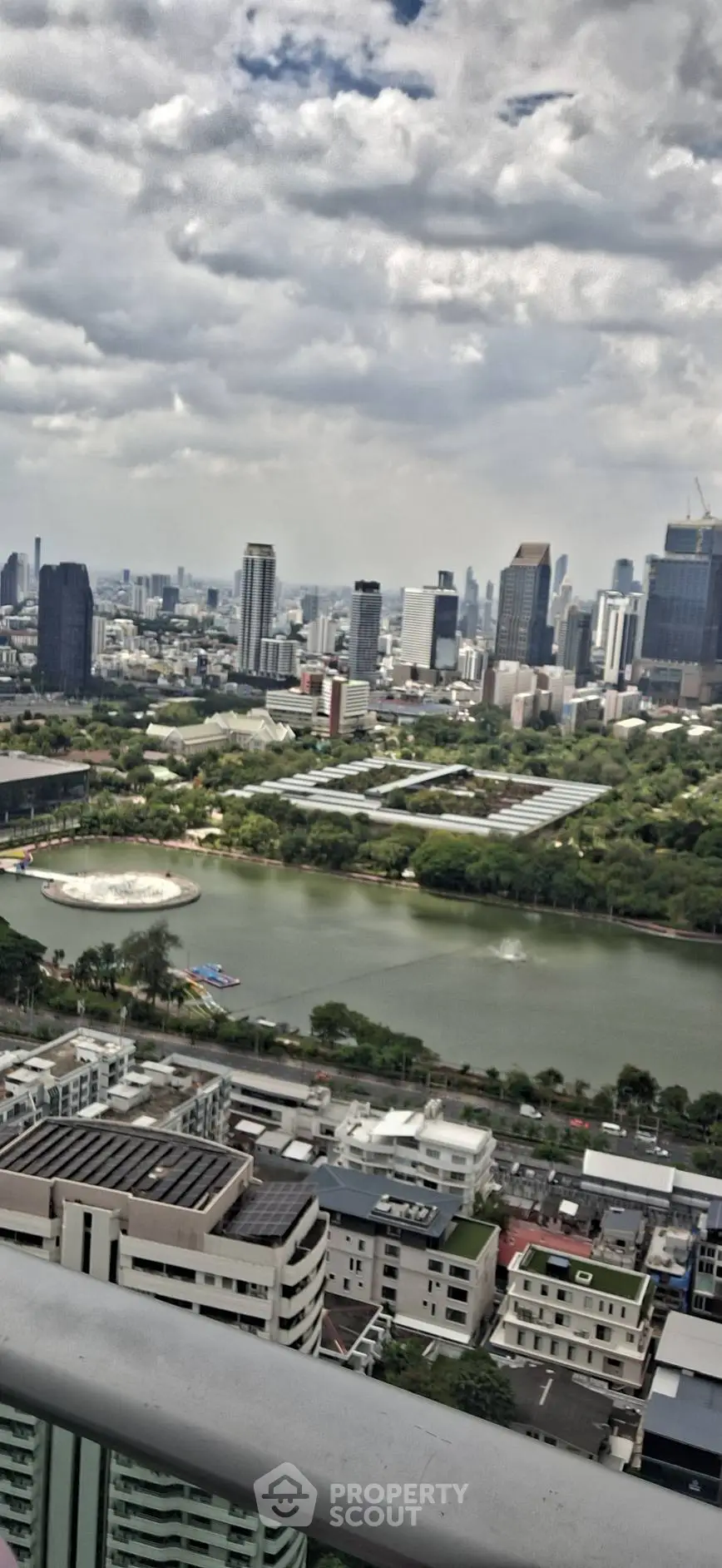 Stunning cityscape view from high-rise balcony overlooking urban skyline and park.